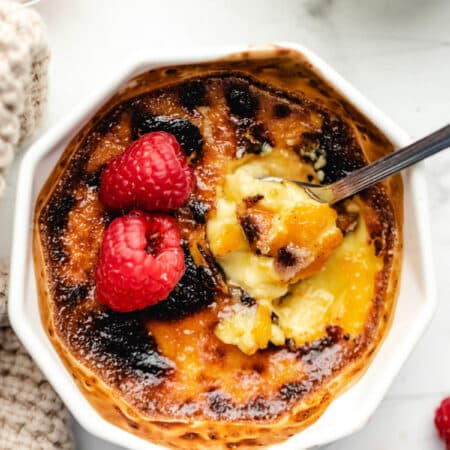 A spoon scooping up a bite of creme bruhlee from a ramekin.