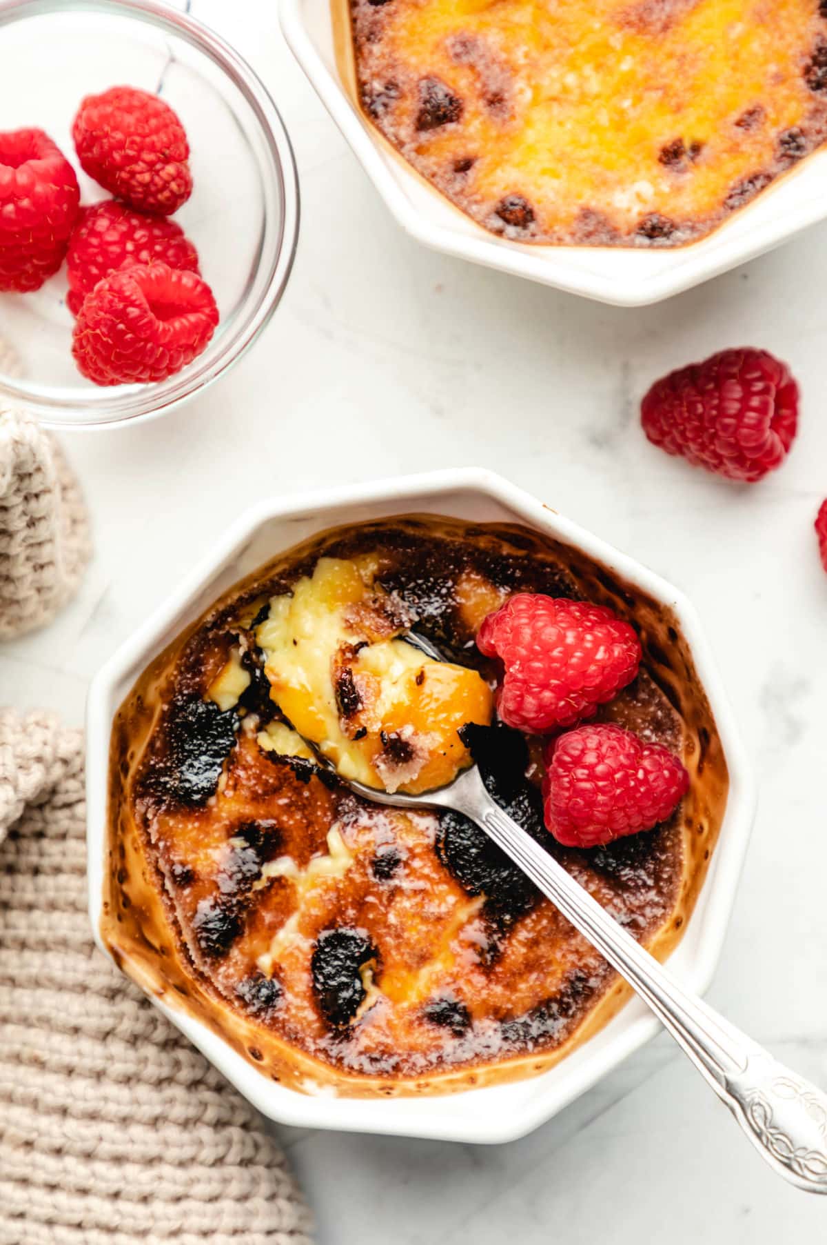 A ramekin full of creme bruhlee with a silver spoon in it. 