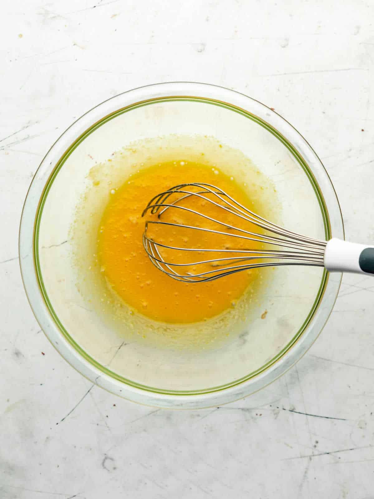 Egg and sugar mixture whisked in a glass mixing bowl. 