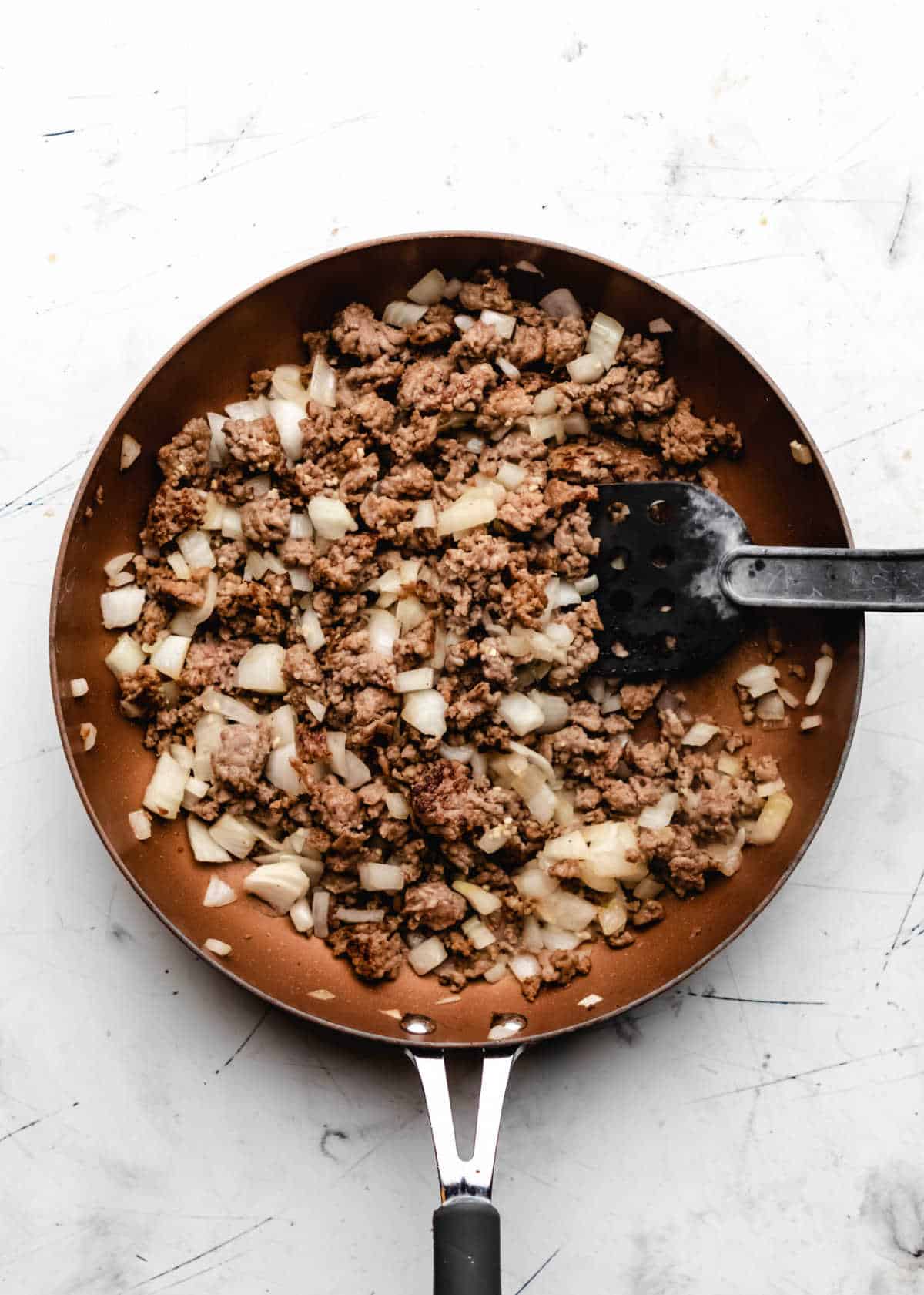 Cooked garlic onion and Italian sausage in a skillet. 