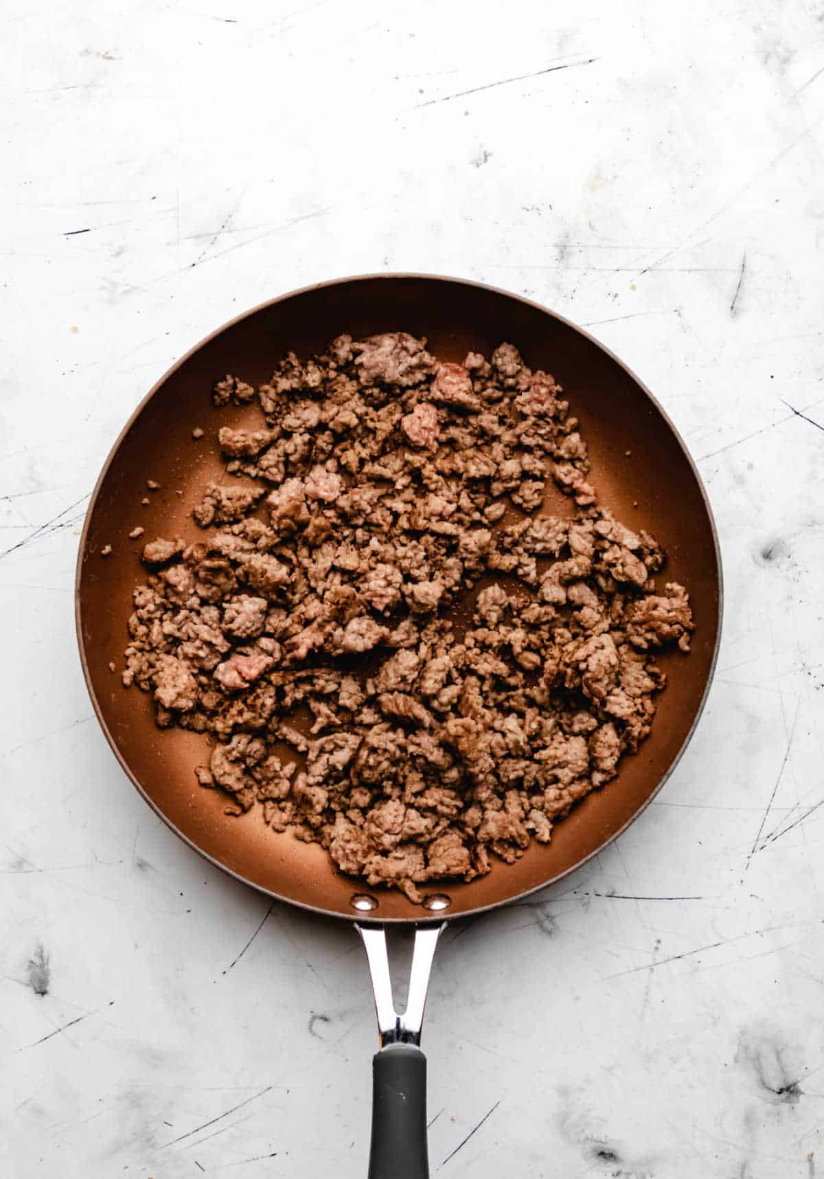 A skillet with browned Italian sausage in it. 