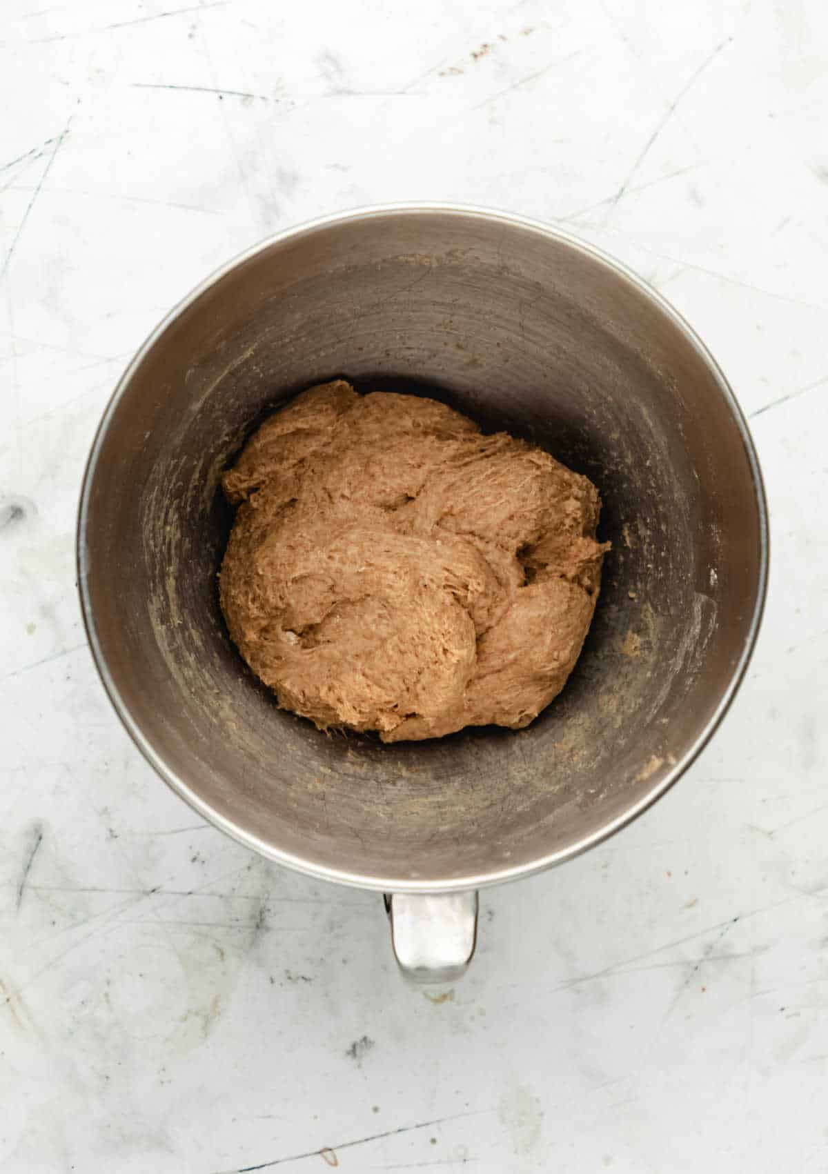 Whole wheat roll dough in a silver mixing bowl. 