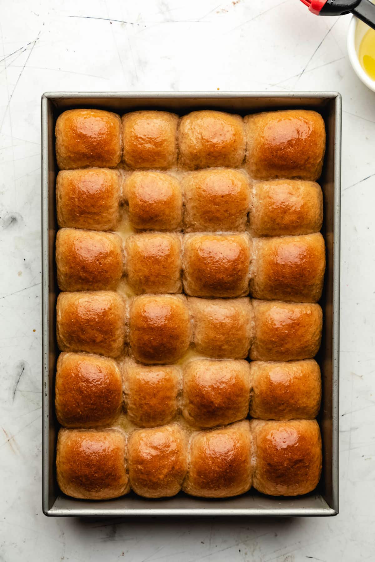 A pan of whole wheat dinner rolls with butter brushed on them. 