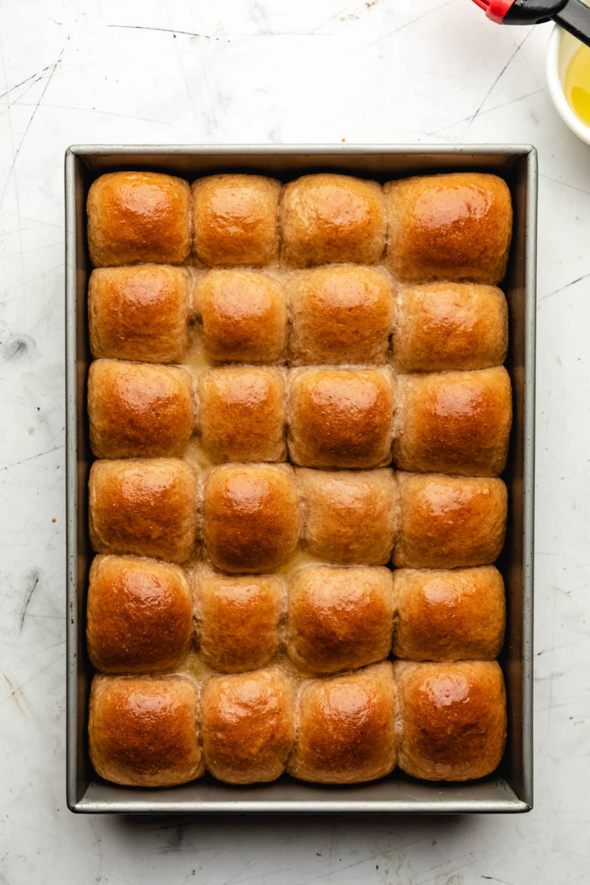 A pan of whole wheat dinner rolls with butter brushed on them.