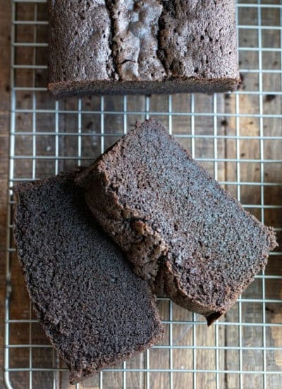 Two slices of chocolate pound cake next to the loaf cake.