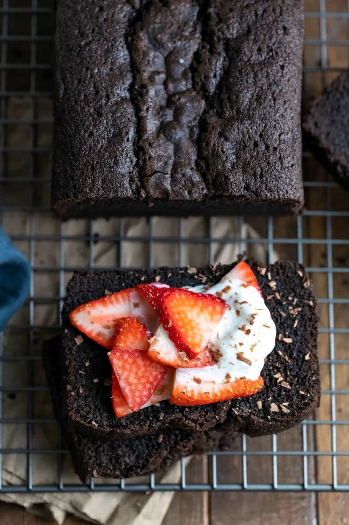 A piece of chocolate pound cake topped with sliced strawberries and whipped cream.