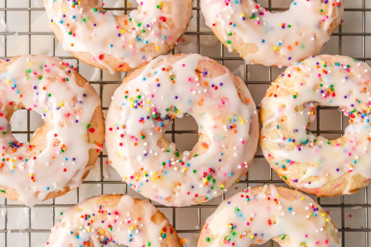Glazed funfetti baked donuts on a wire cooling rack.