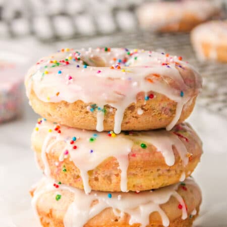 Three baked Funfetti donuts stacked on top of each other.