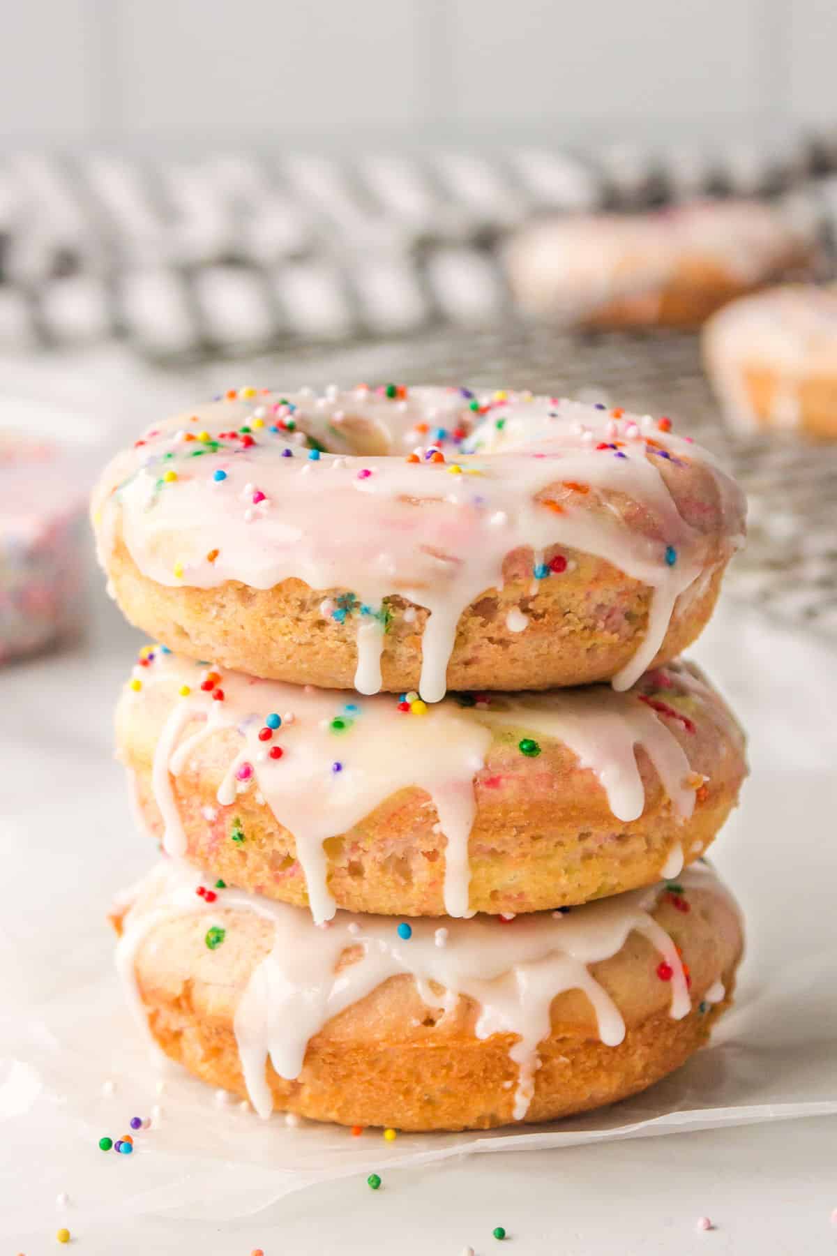 Three baked Funfetti donuts stacked on top of each other. 