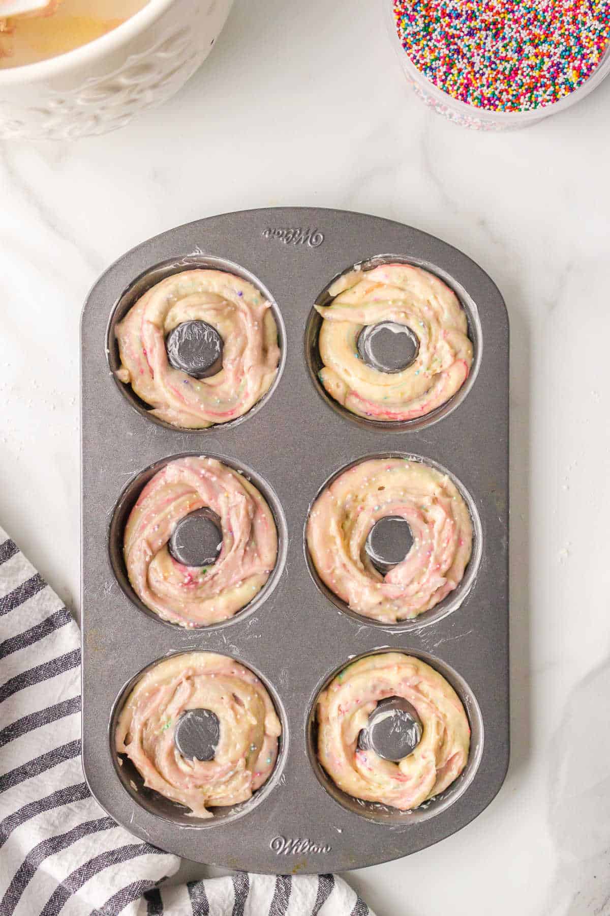 Funfetti donut batter in a donut pan.