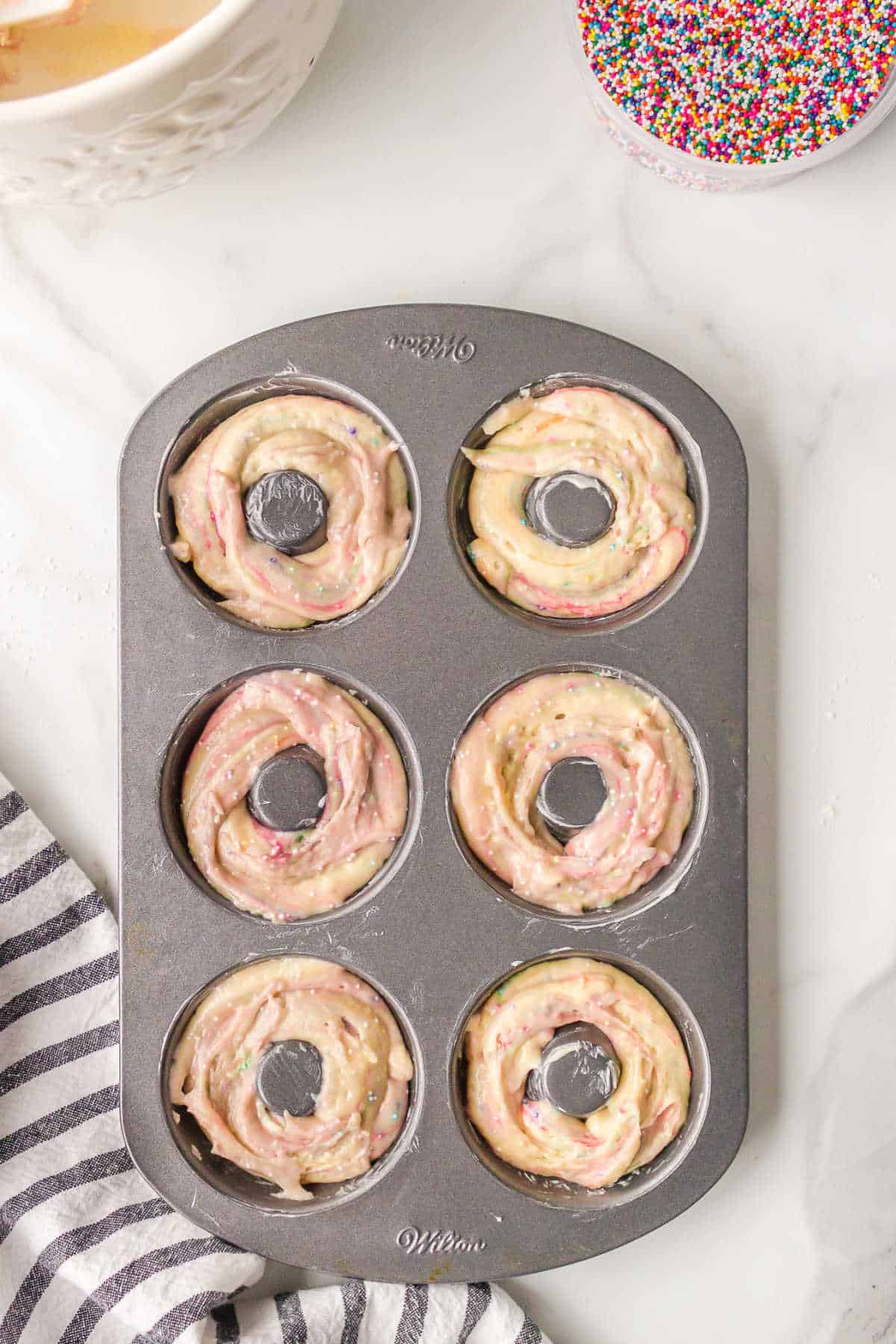 Funfetti donut batter in a donut pan. 