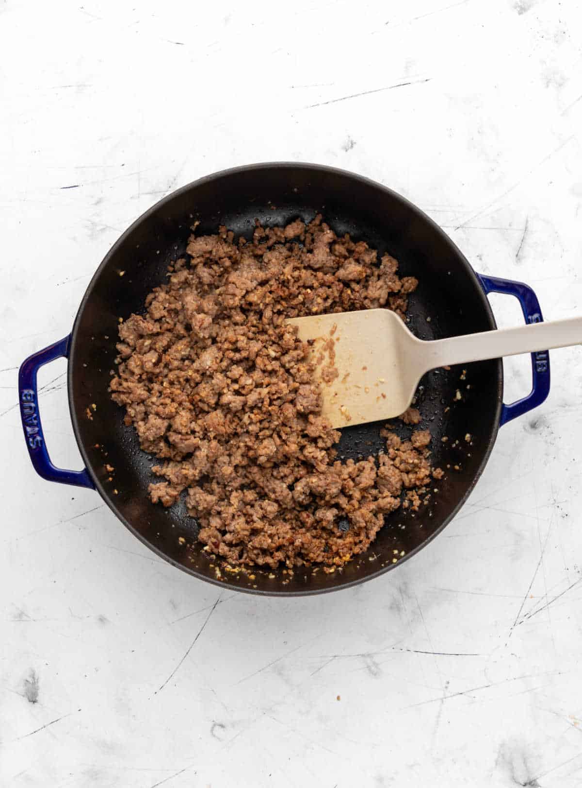 A spatula stirring red wine into browned ground beef. 