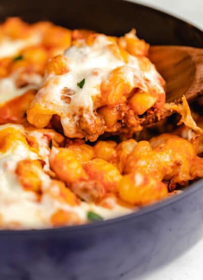 A wooden spoon holding a scoop of baked gnocchi.