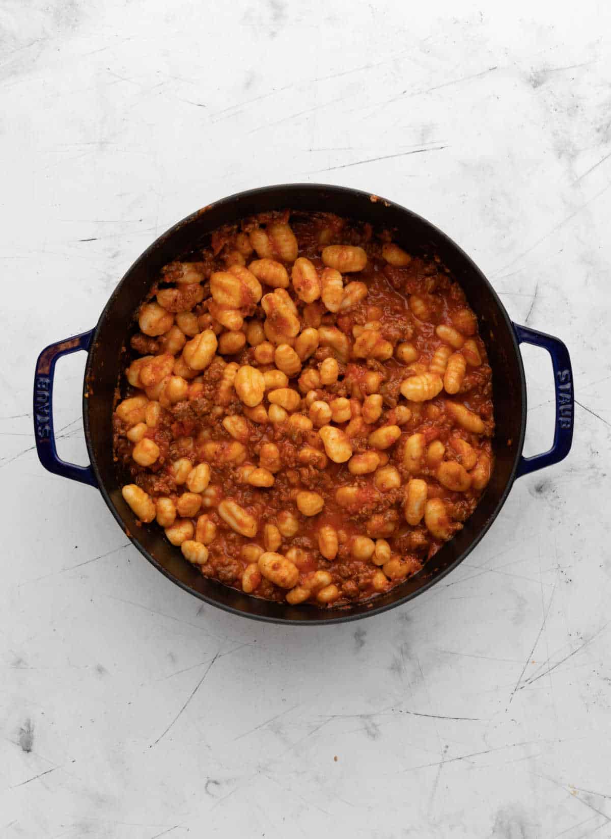 Gnocchi, marinara, and Italian sausage in a skillet. 