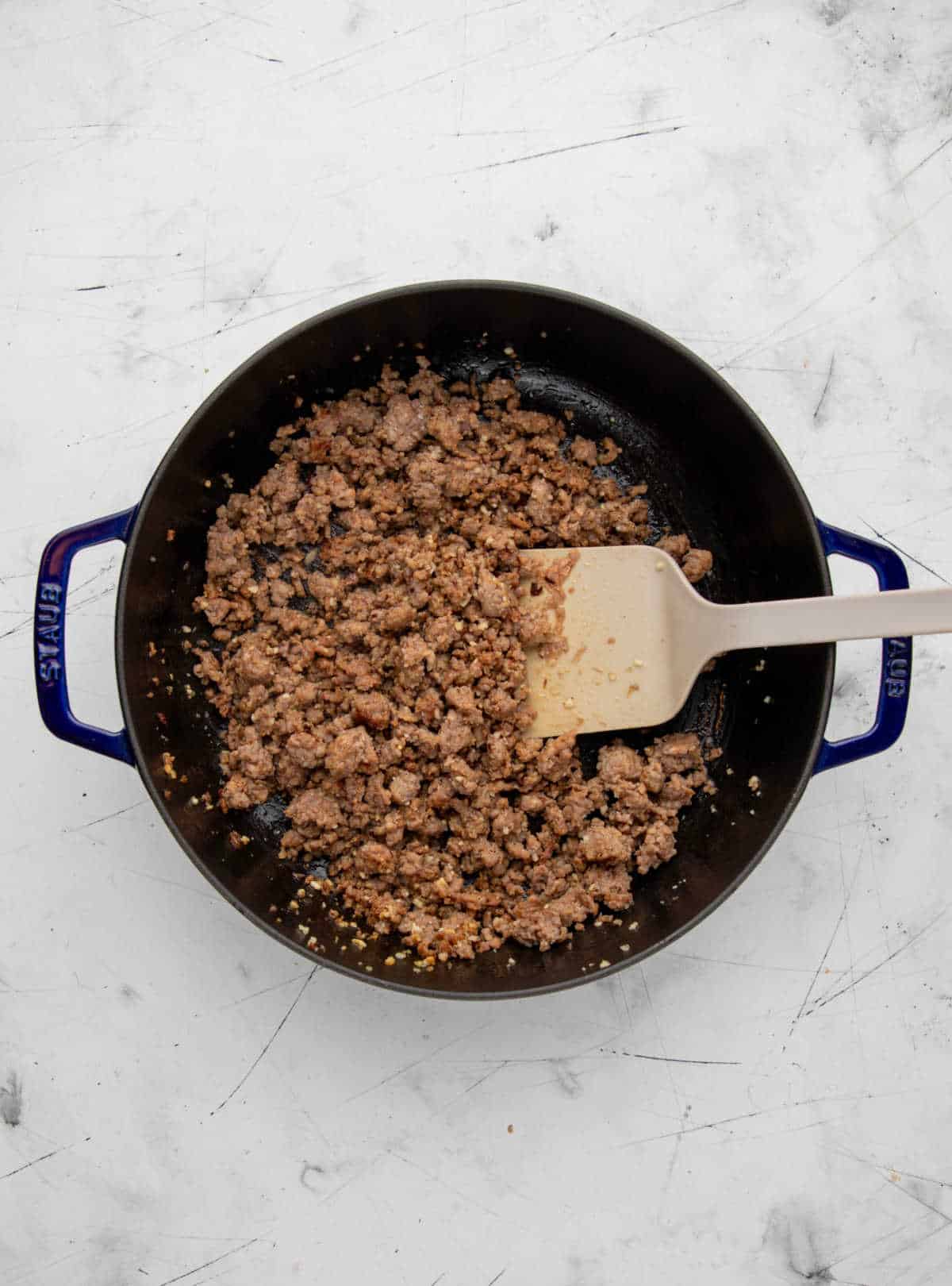 Browned Italian sausage and minced garlic in a skillet.