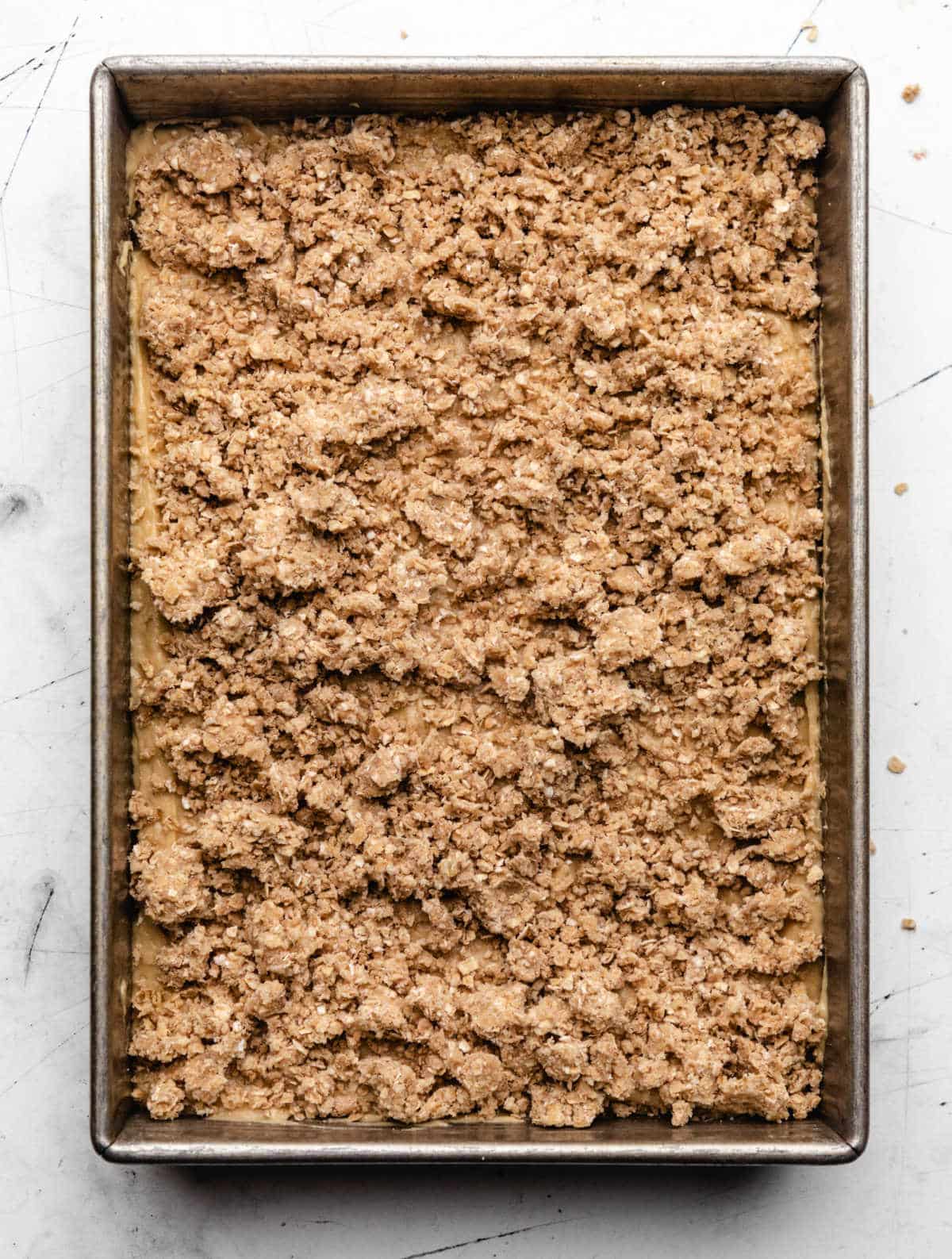 Crumb topping on banana cake batter in a cake pan.