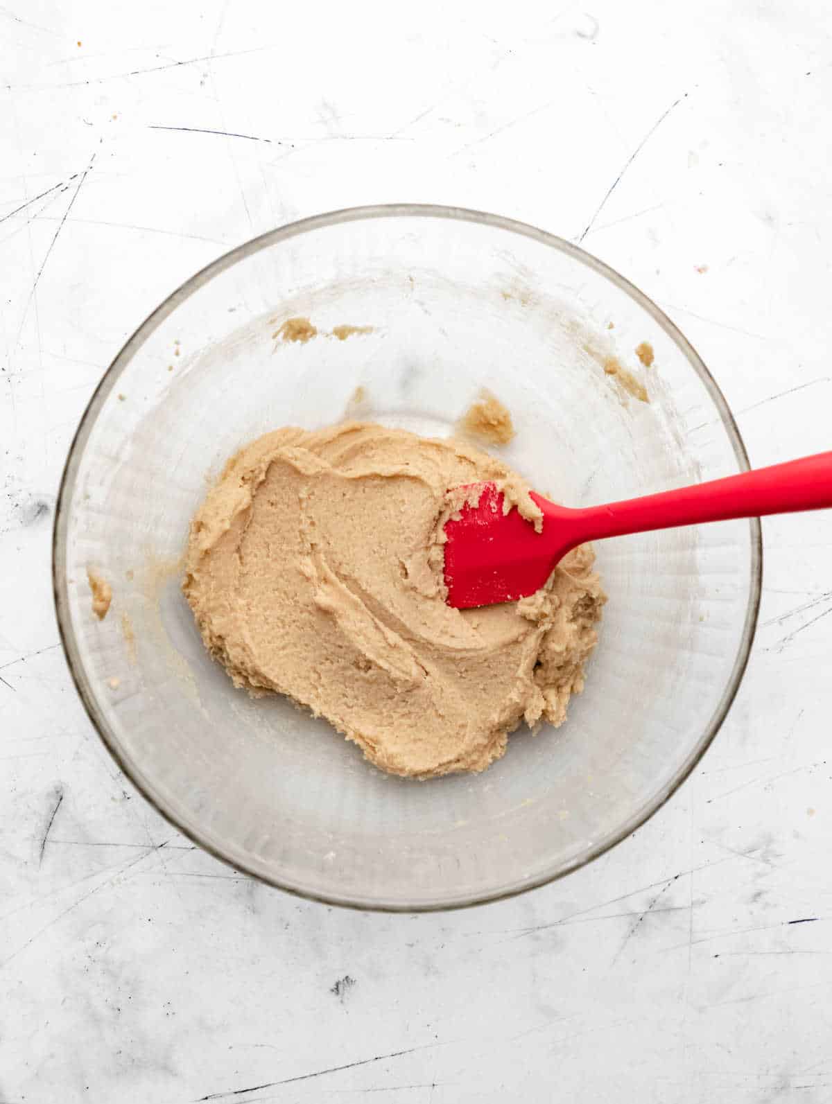 Butter and sugar mixed together in a glass mixing bowl. 