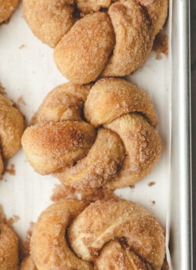 Rows of cinnamon sugar knots on a baking tray.