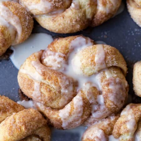 Cinnamon sugar knots topped with glaze on a slate background.