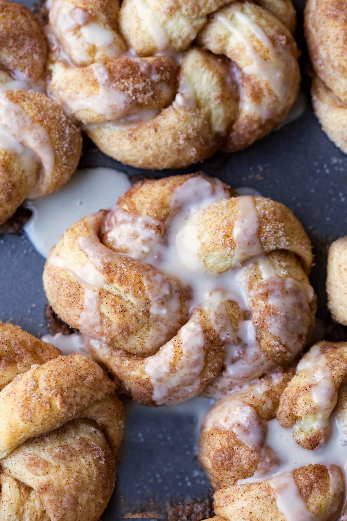 Cinnamon sugar knots topped with glaze on a slate background.