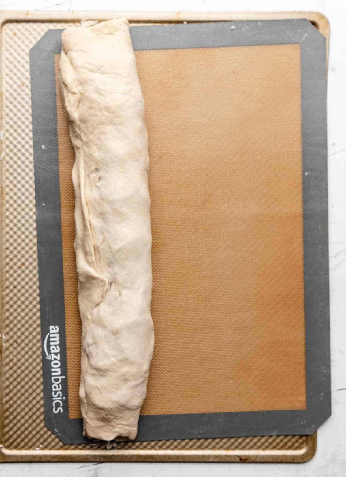 Rolled up pepperoni bread on a silicone baking mat. 
