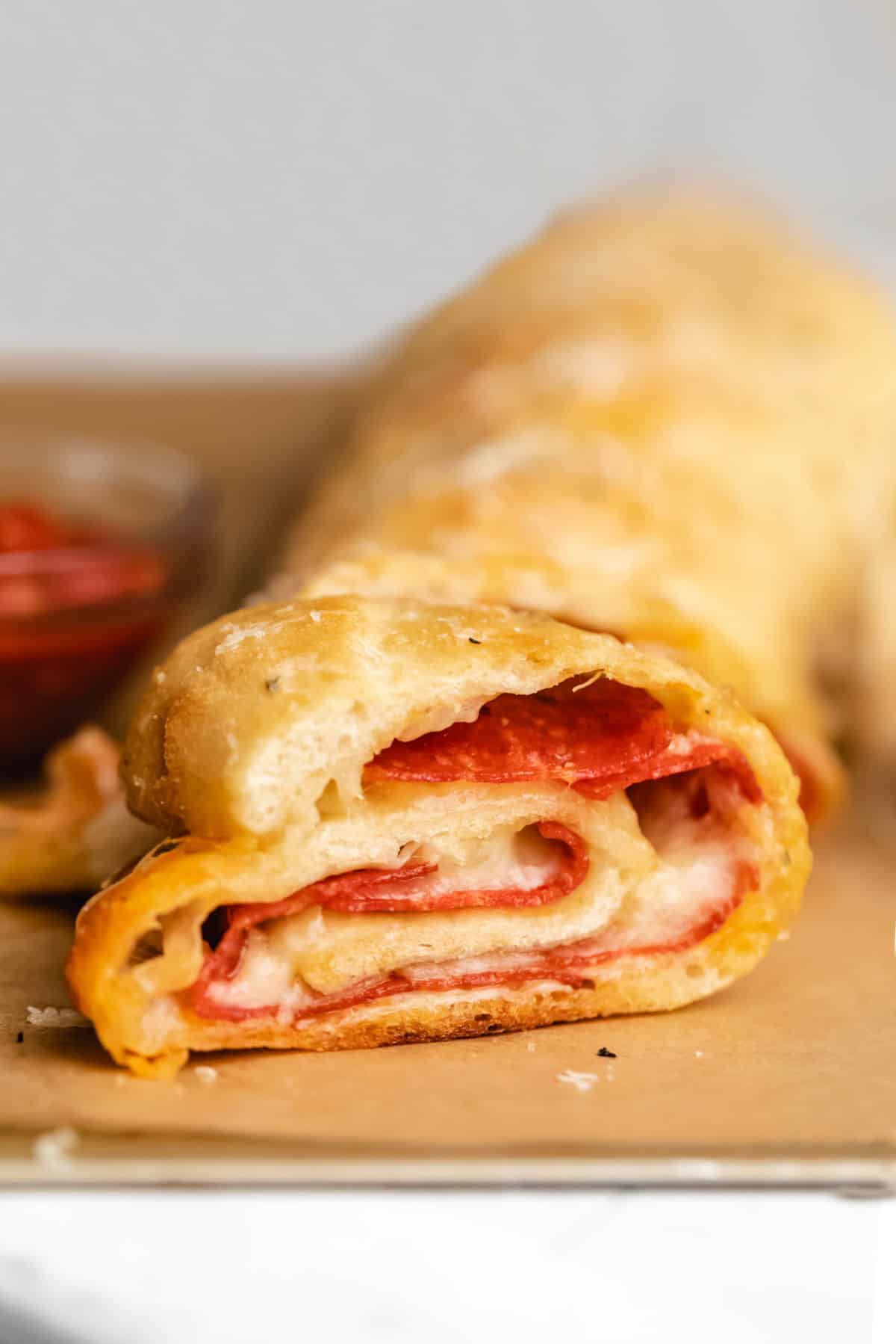 A loaf of pepperoni bread on a piece of brown parchment paper.