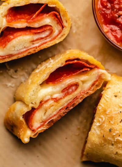 Slices of pepperoni bread next to a dish of pizza sauce.