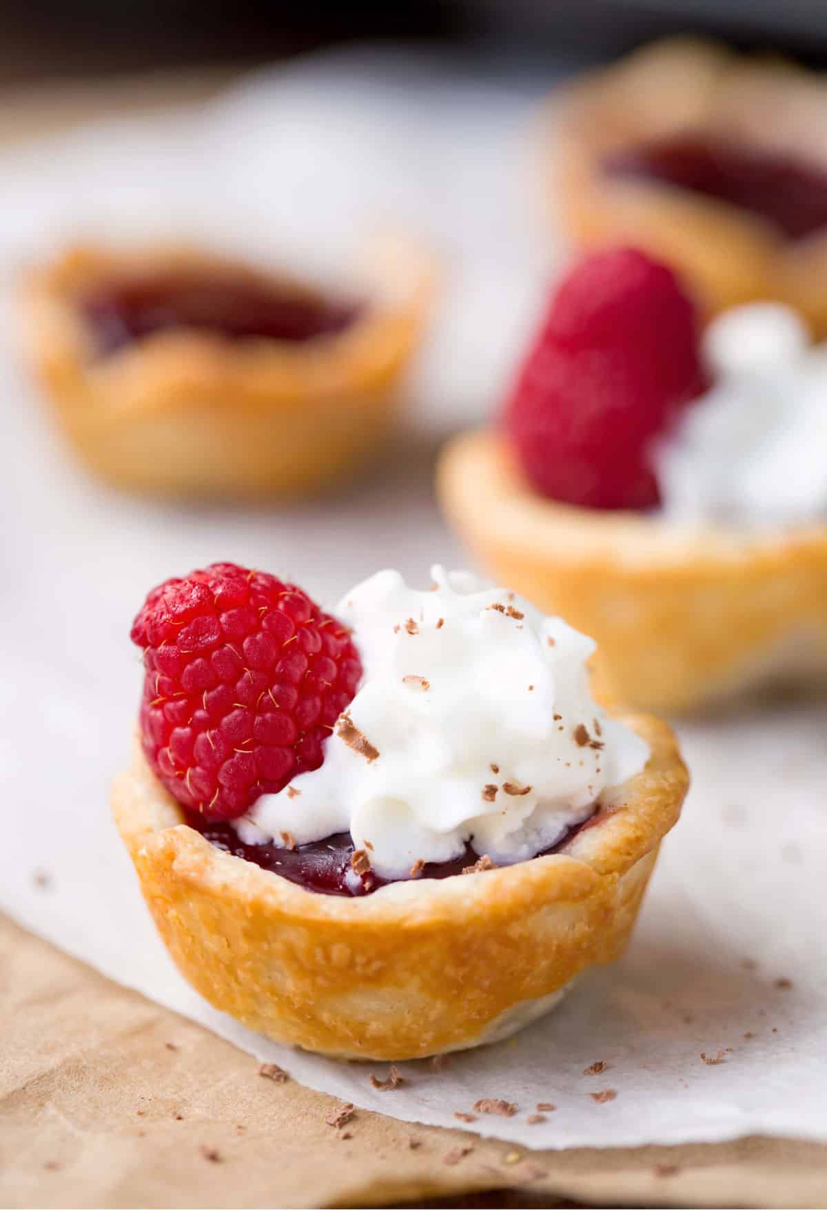 Raspberry tassies on a piece of parchment paper. 