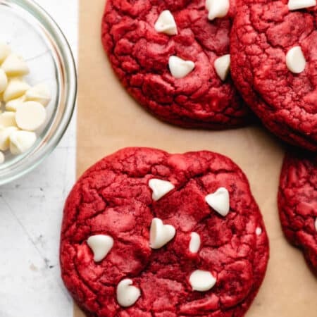 A red velvet cookie next to a stack of red velvet cookies.