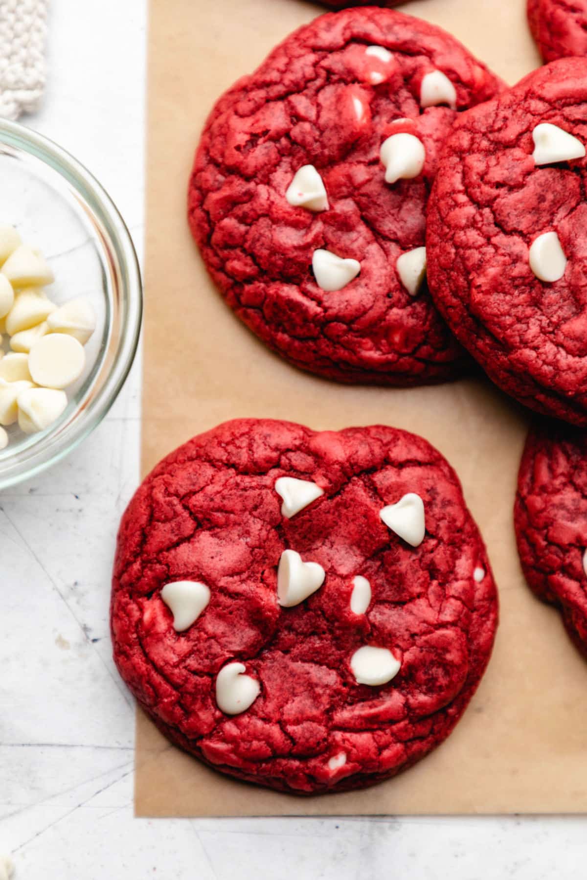 A red velvet cookie next to a stack of red velvet cookies.