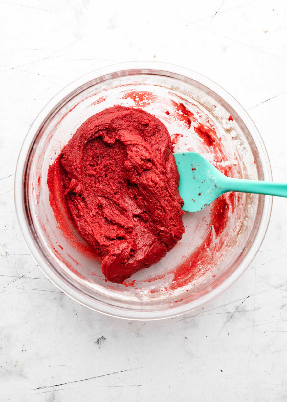 Red velvet cookie dough in a glass mixing bowl.