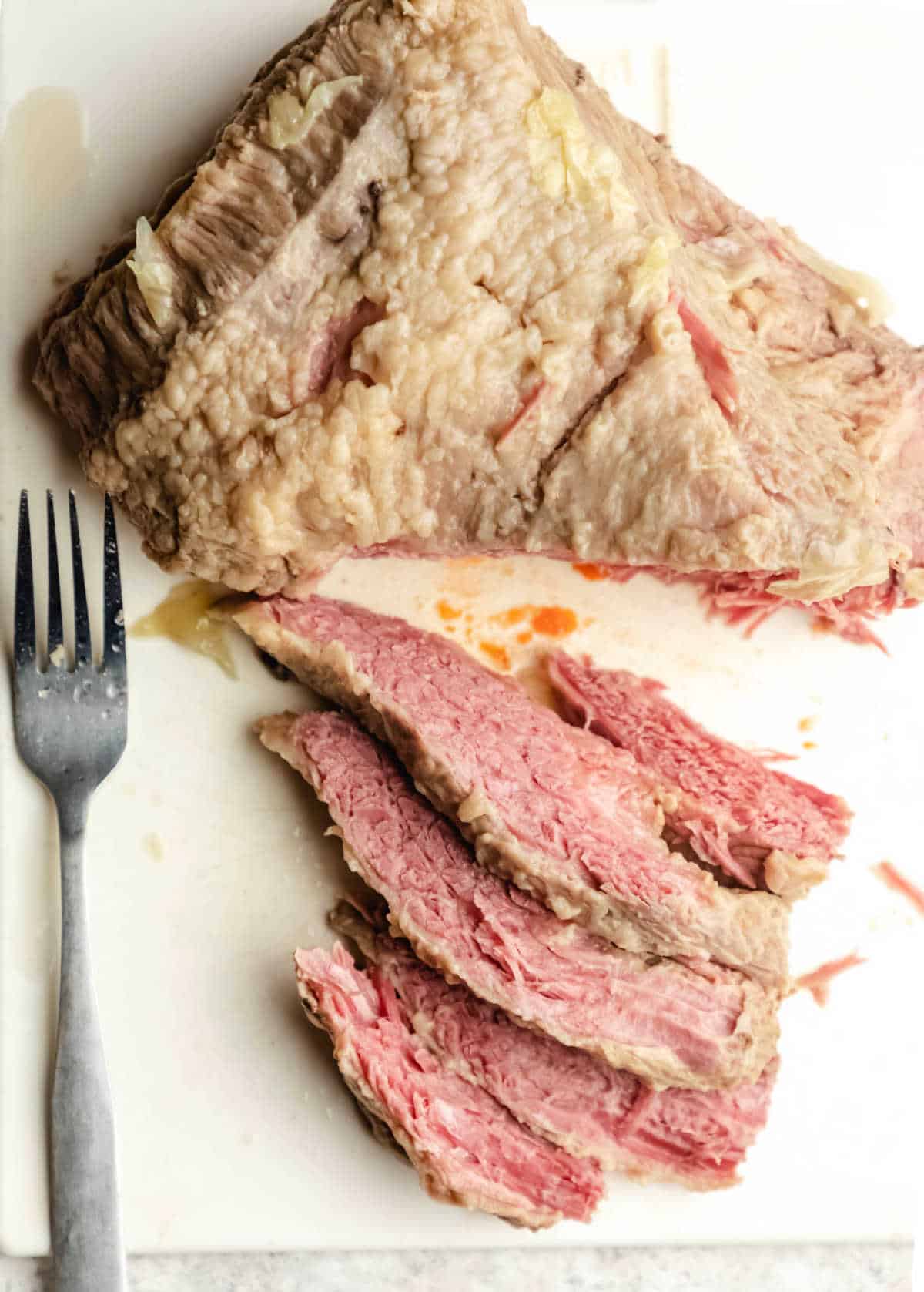 Slices of corned beef on a white cutting board. 