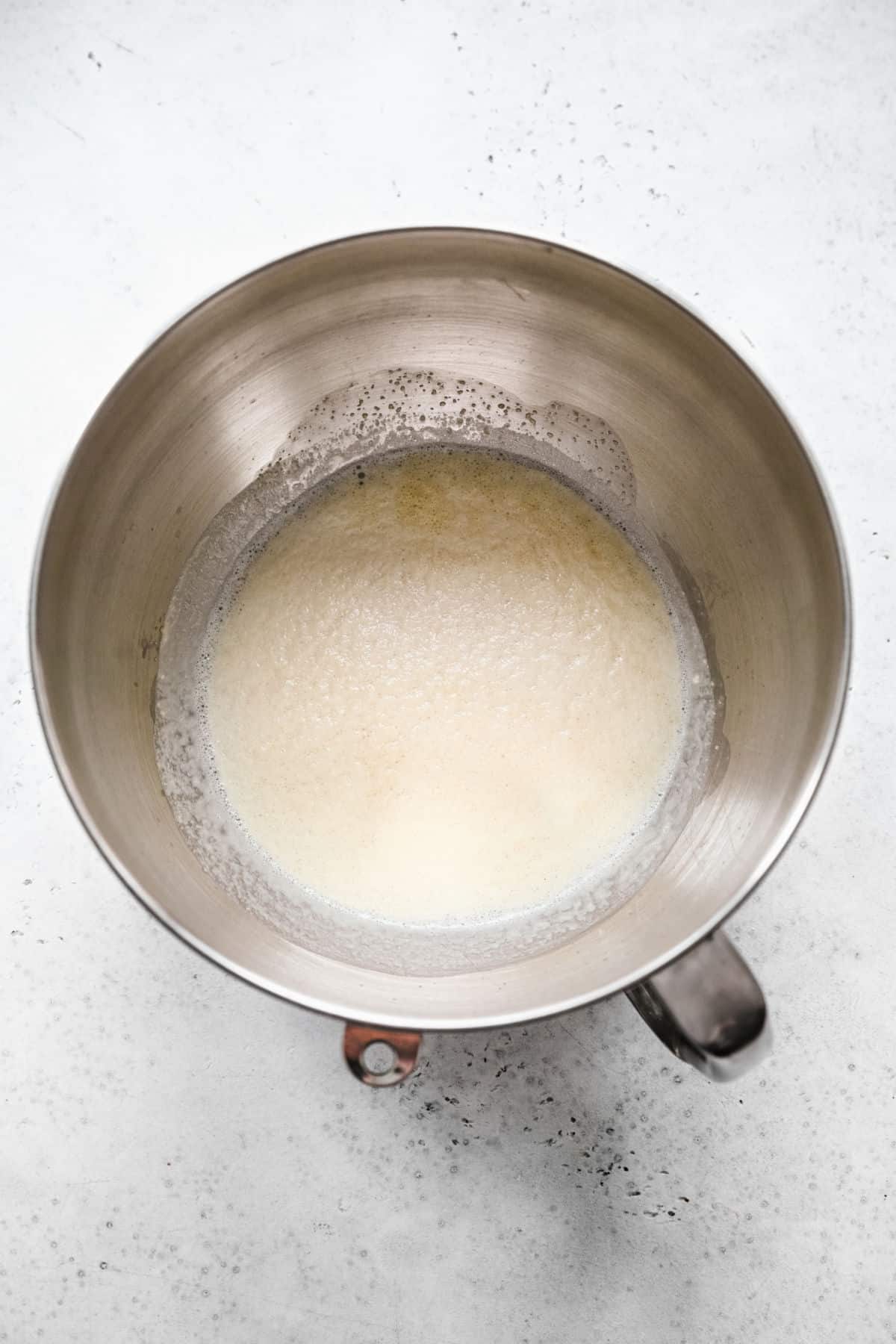 Foamy yeast mixture in a silver mixing bowl. 