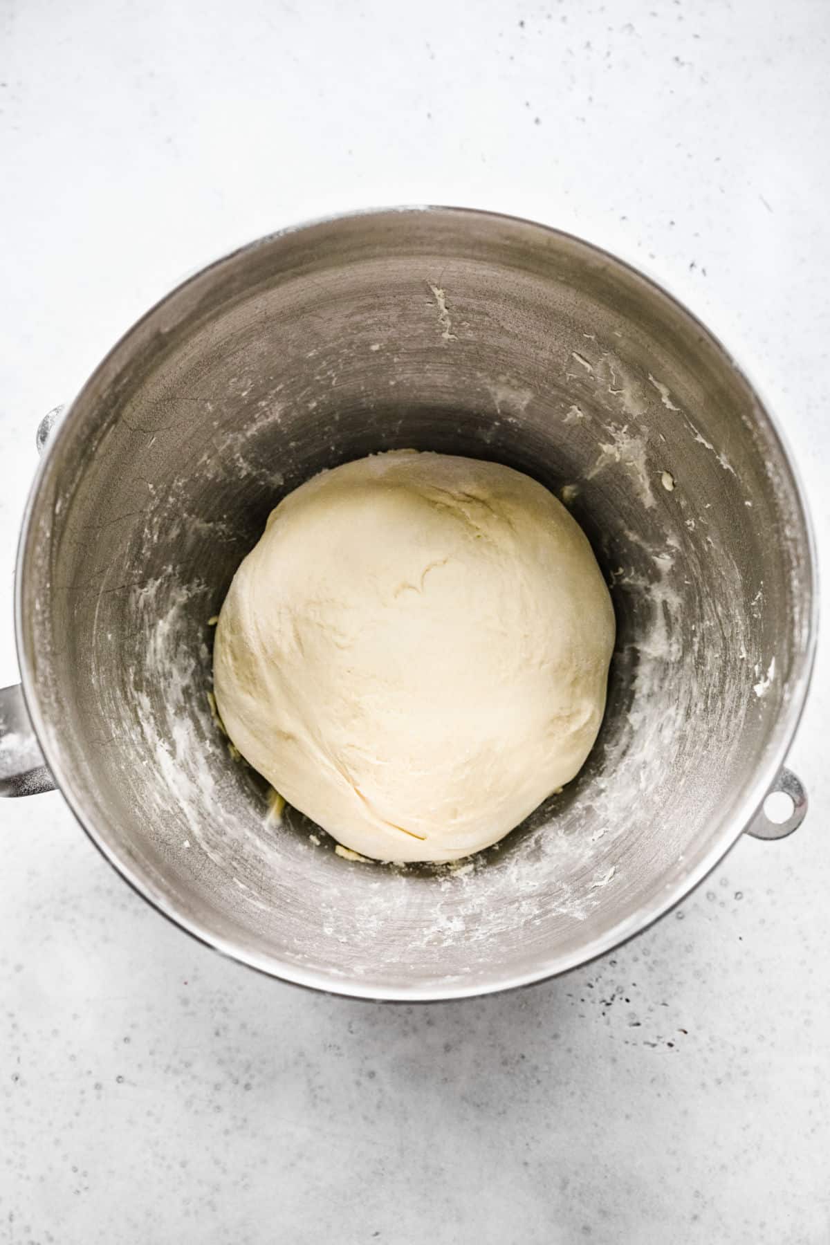 Cinnamon roll bite dough in a silver mixing bowl. 