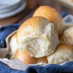 Dinner rolls in a blue linen napkin lined basket.