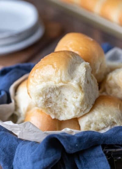 Dinner rolls in a blue linen napkin lined basket.