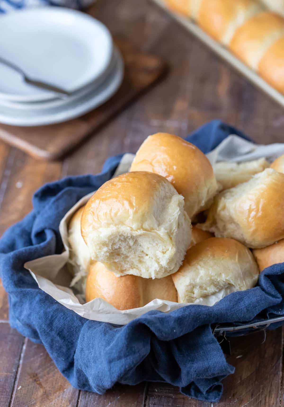 A basket of dinner rolls in front of the pan of rolls. 