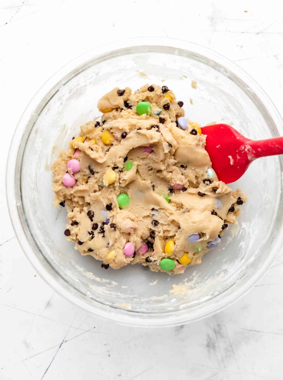 Easter M&M cookie dough in a glass mixing bowl.