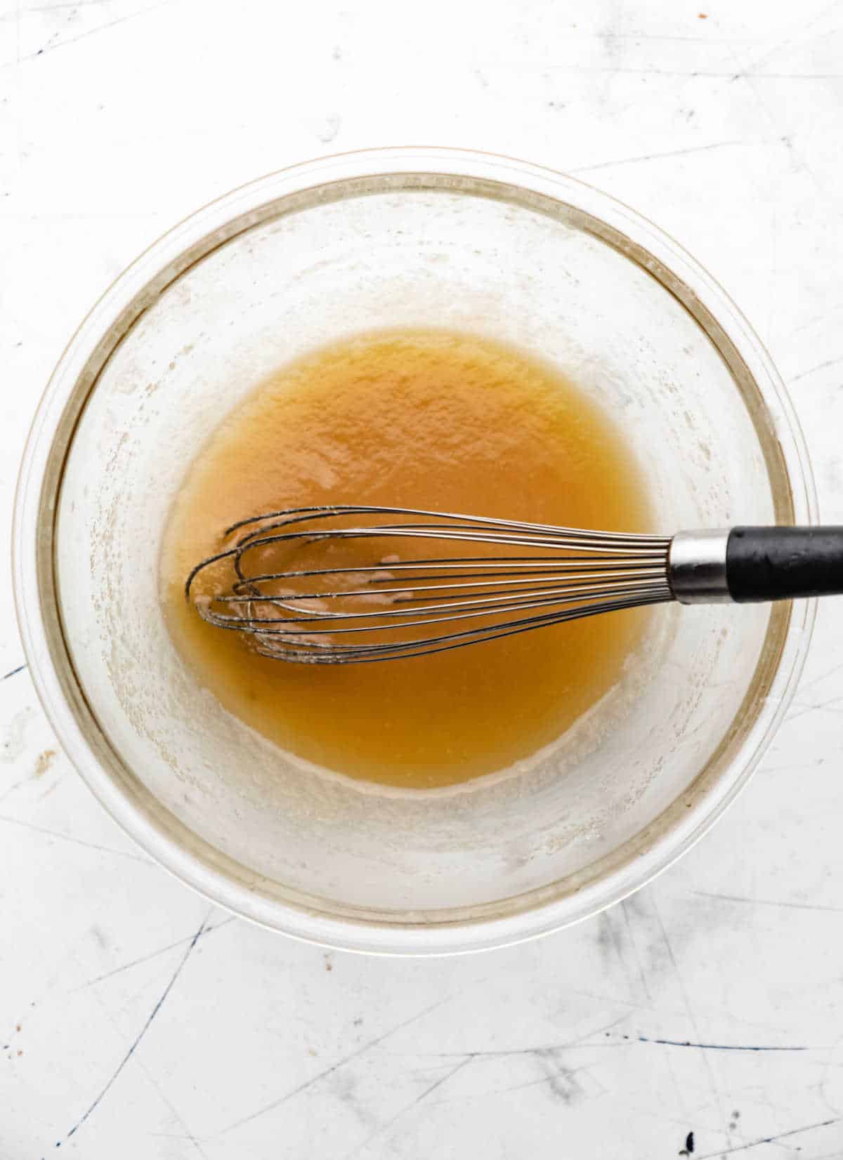 Melted butter and sugars whisked together in a glass mixing bowl. 