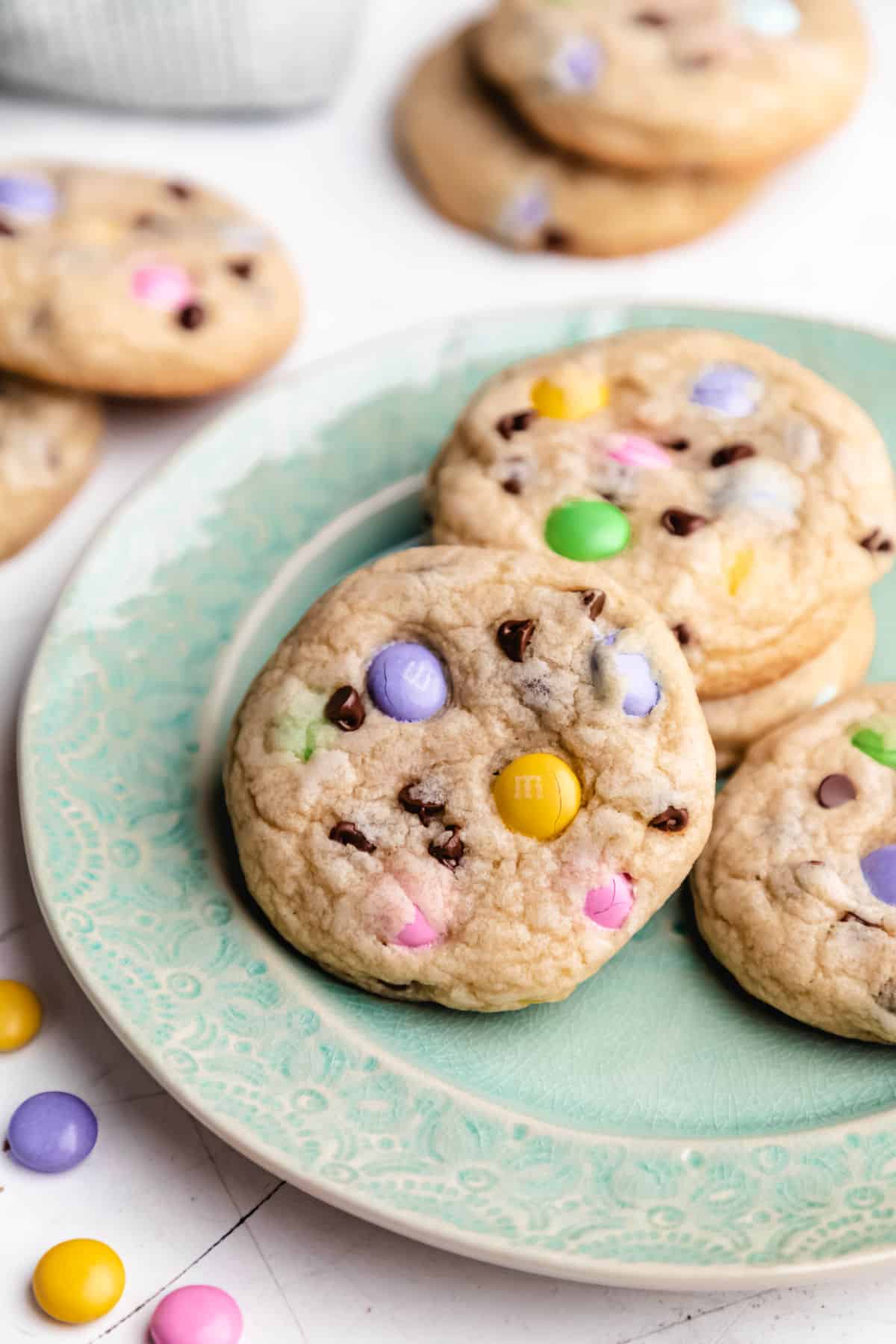 Easter M&M cookies stacked on a teal plate.