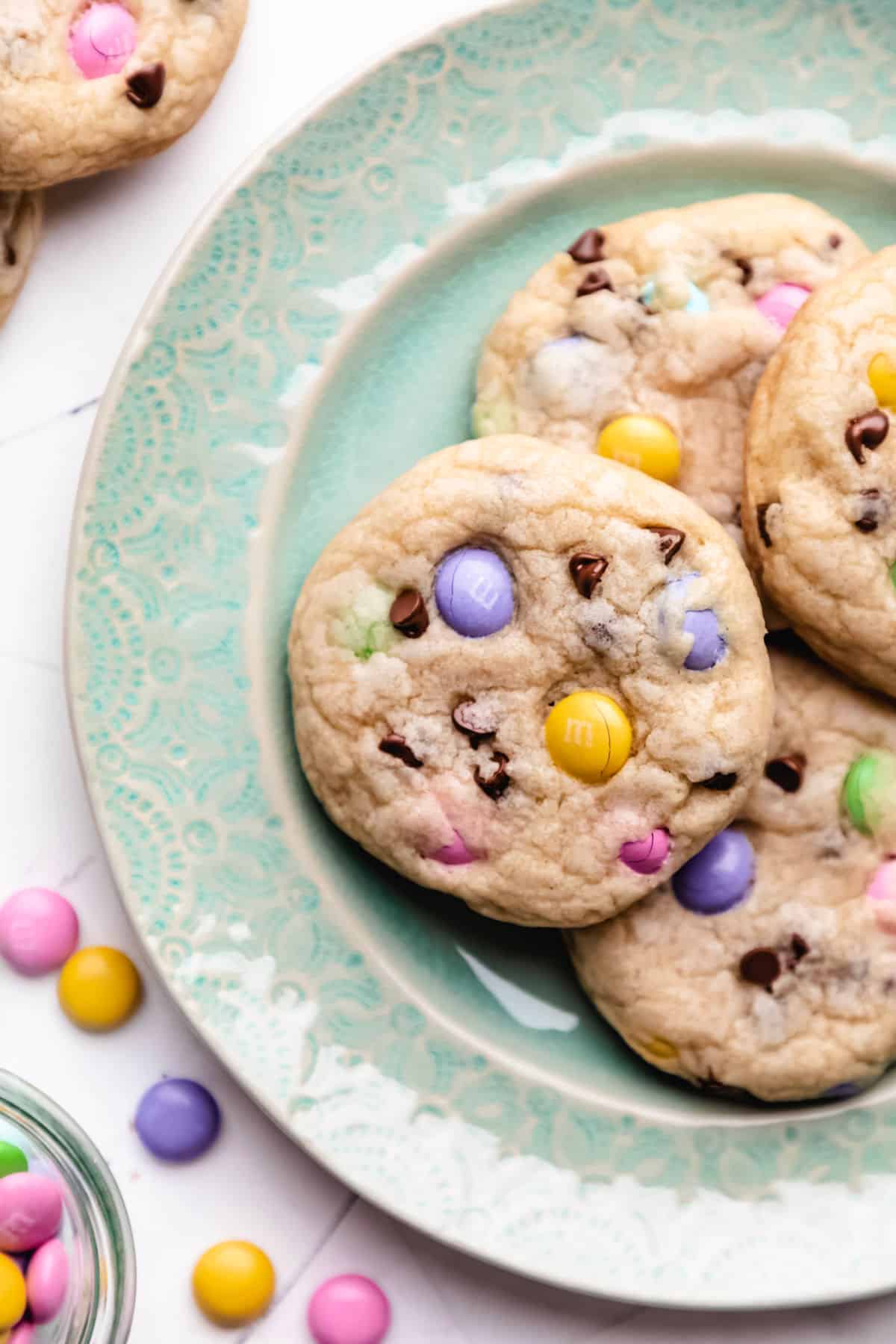 Easter M&M cookies on a teal plate next to scattered M&Ms. 