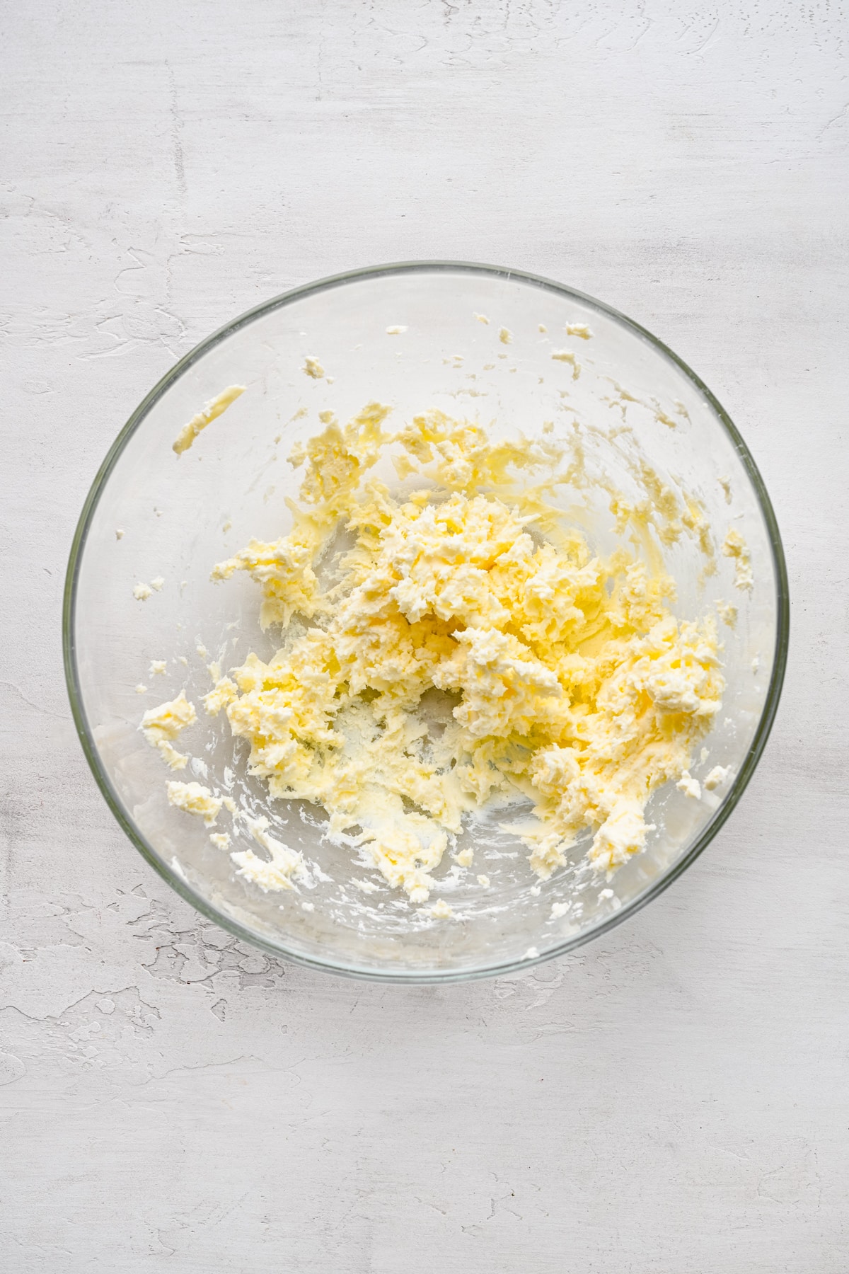 Butter and cream cheese beaten together in a glass mixing bowl.