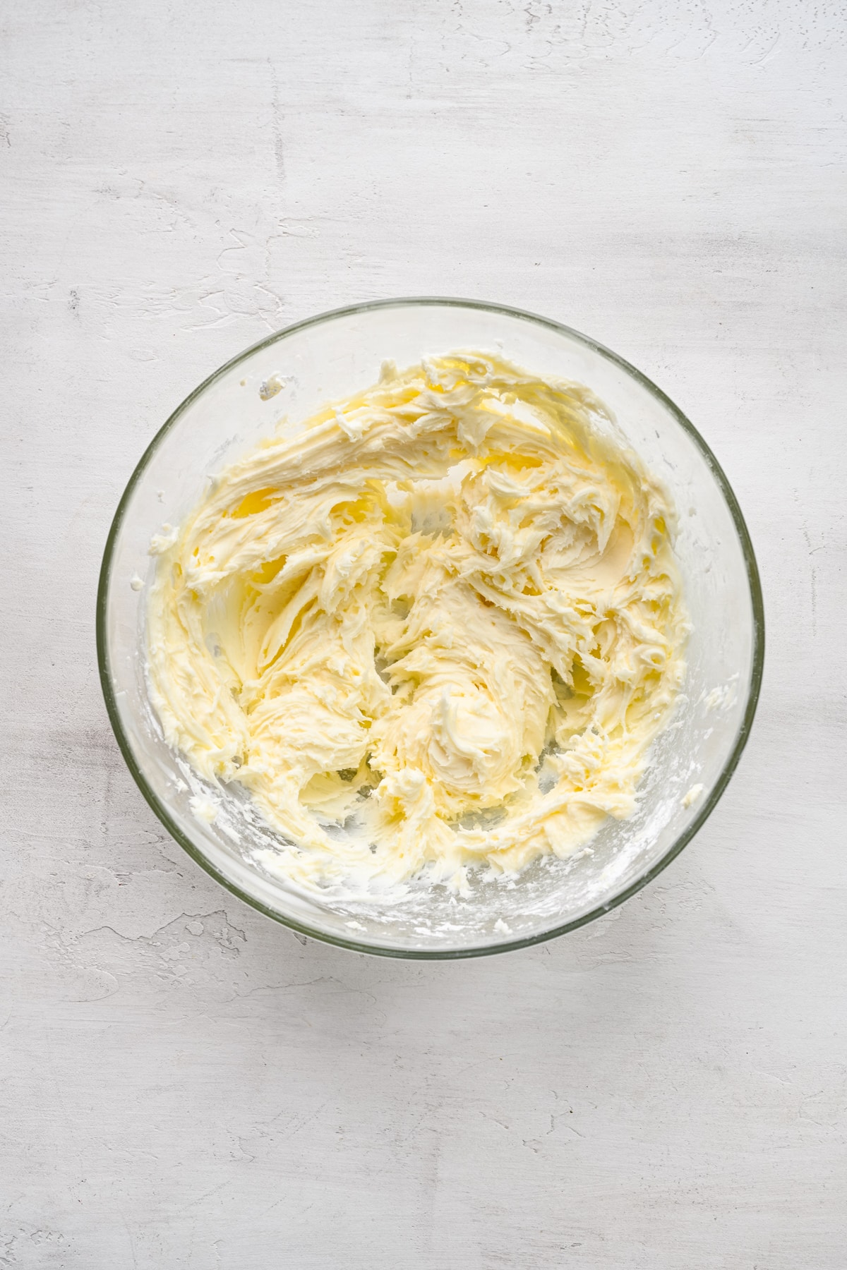 Cream cheese frosting in a glass mixing bowl.