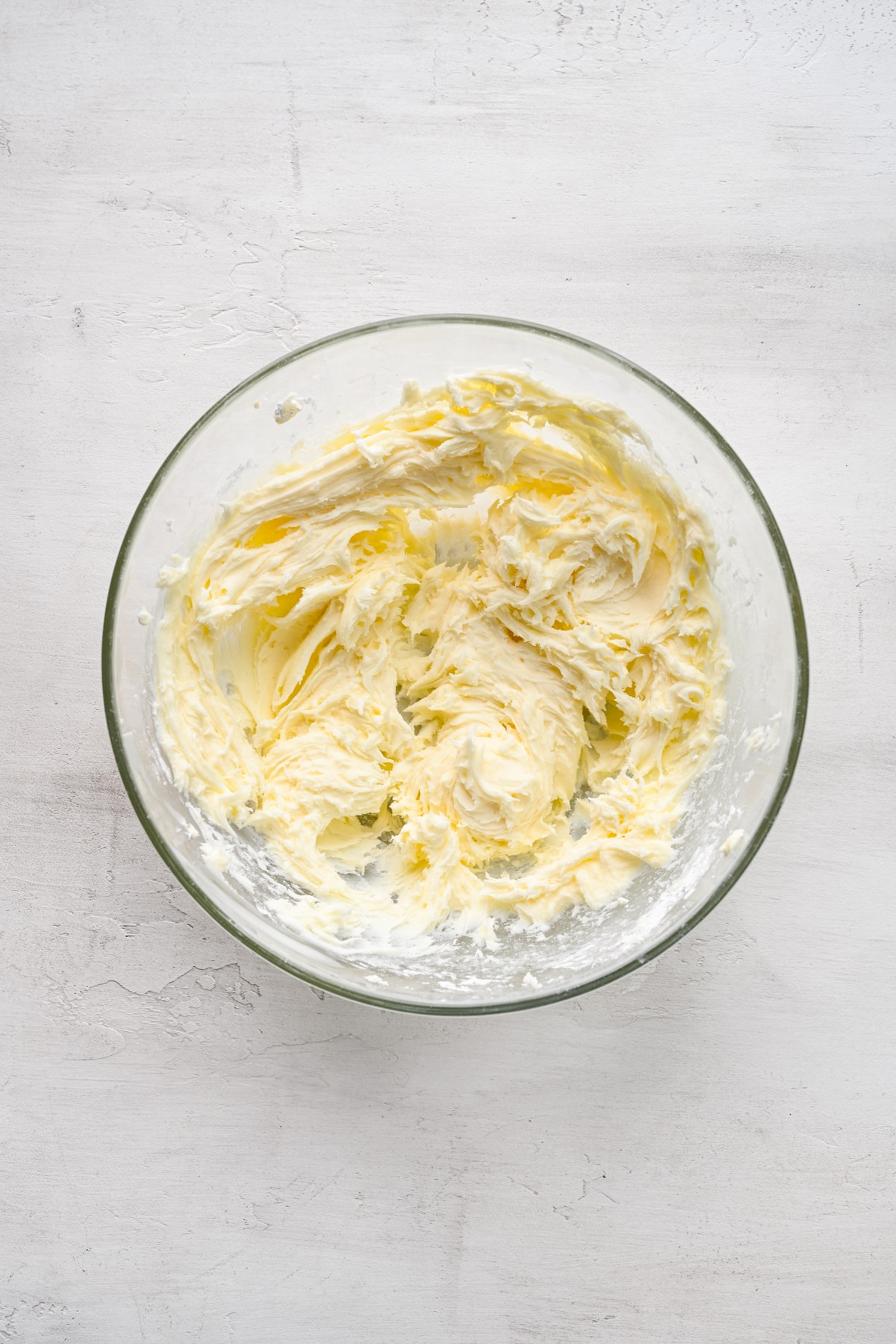 Cream cheese frosting in a glass mixing bowl. 