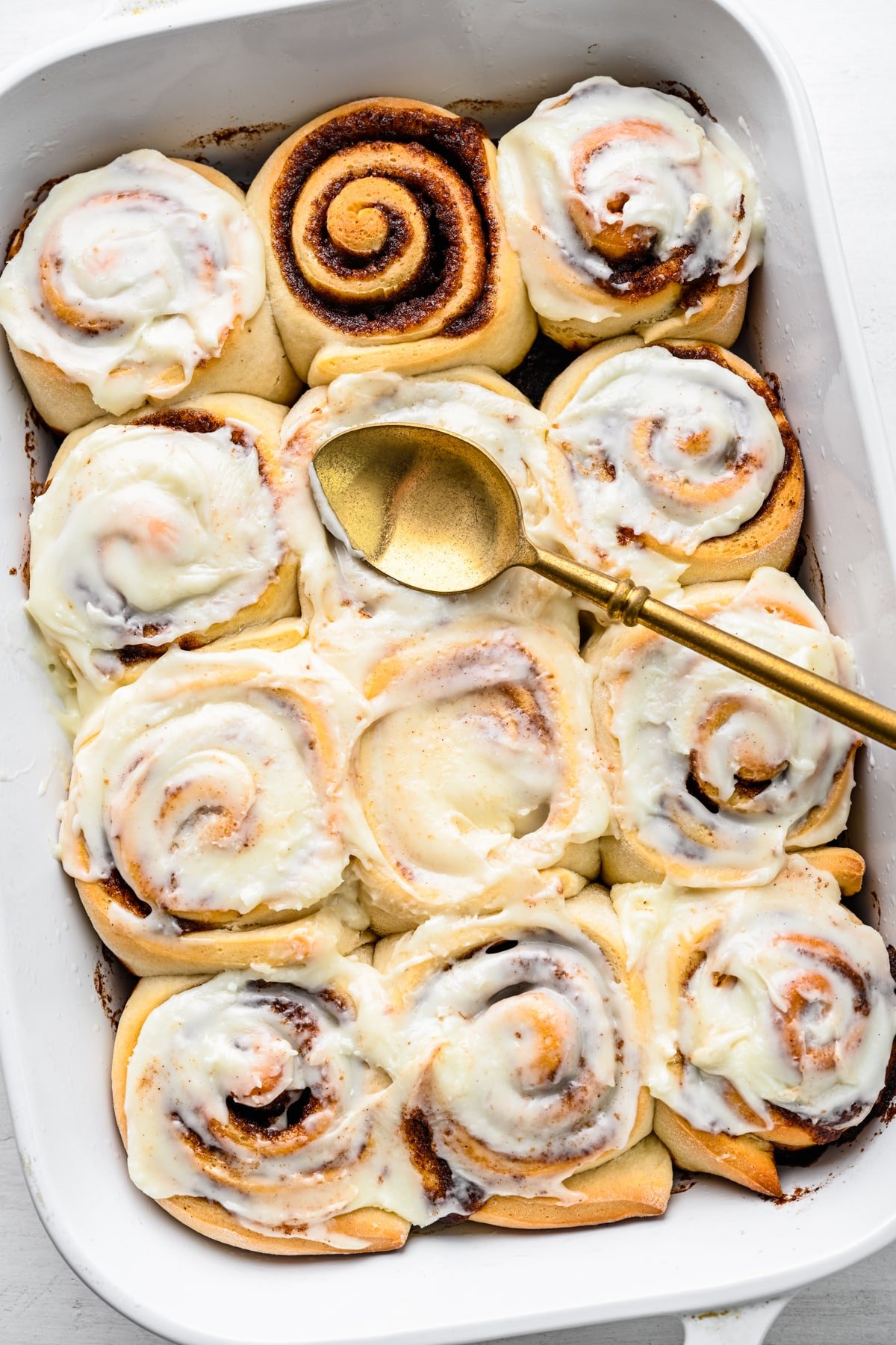 Easy Cinnamon Rolls A pan of frosted cinnamon rolls with one unfrosted cinnamon roll.