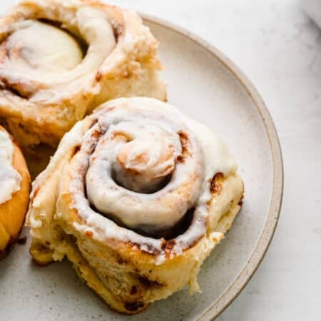 Three homemade cinnamon rolls on a white plate.