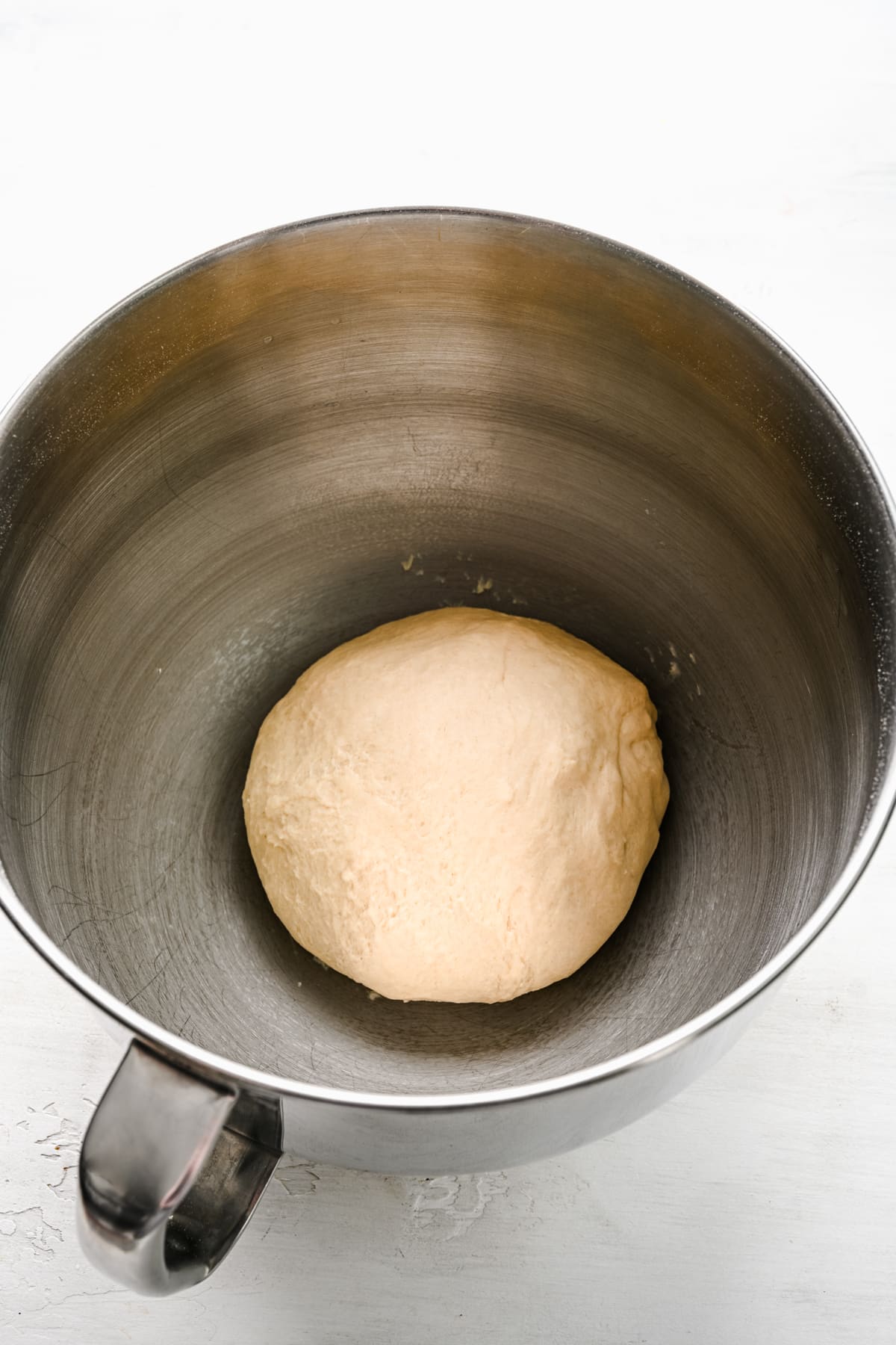Cinnamon roll dough in a silver mixing bowl.