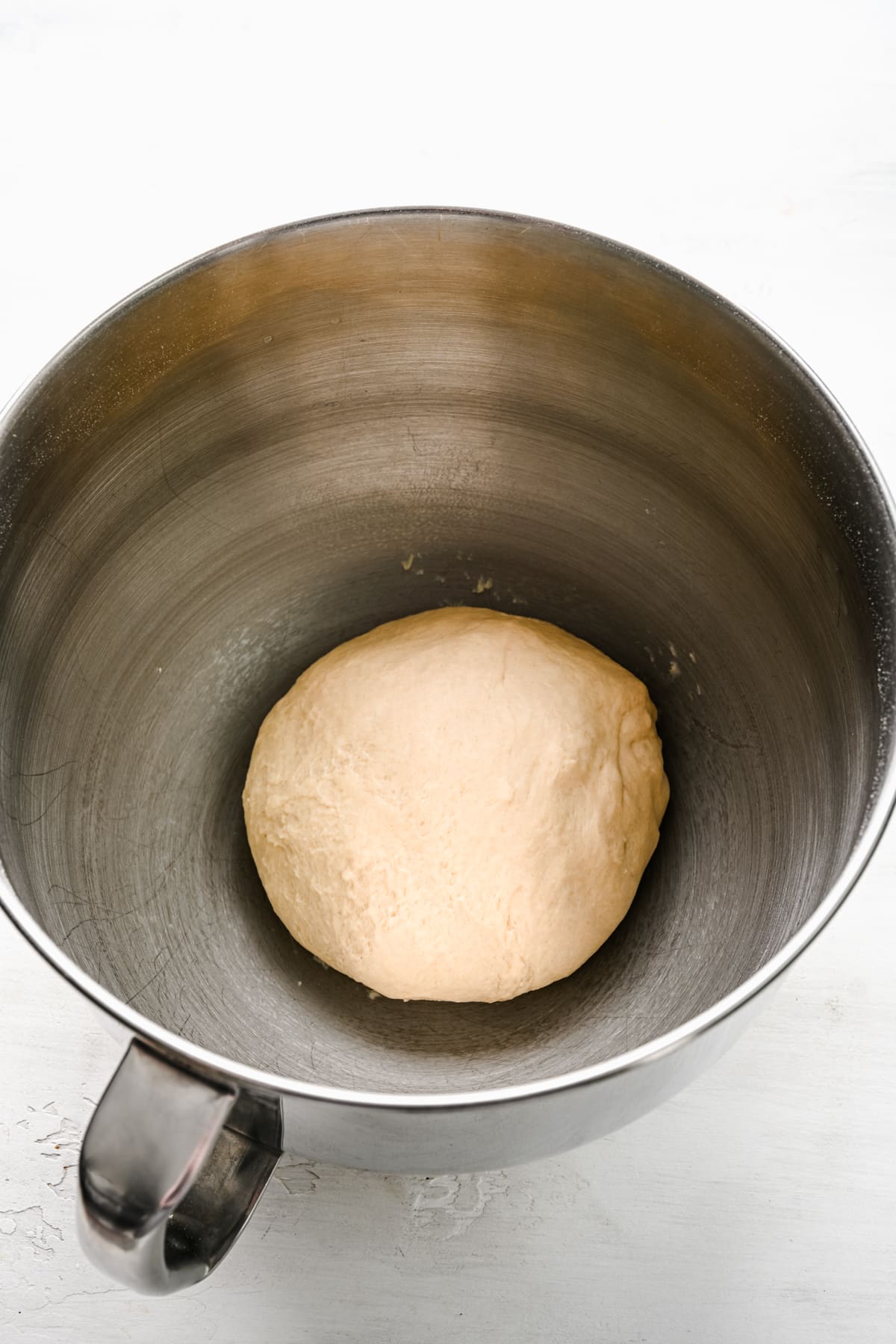 Cinnamon roll dough in a silver mixing bowl. 