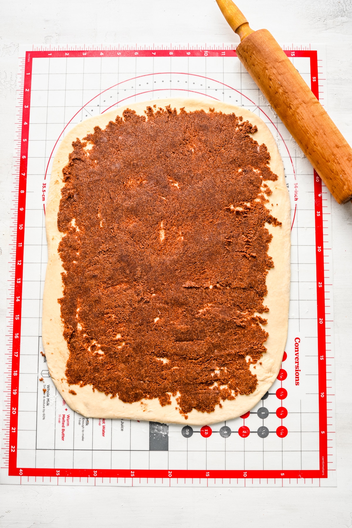 Cinnamon roll filling spread over cinnamon roll dough.