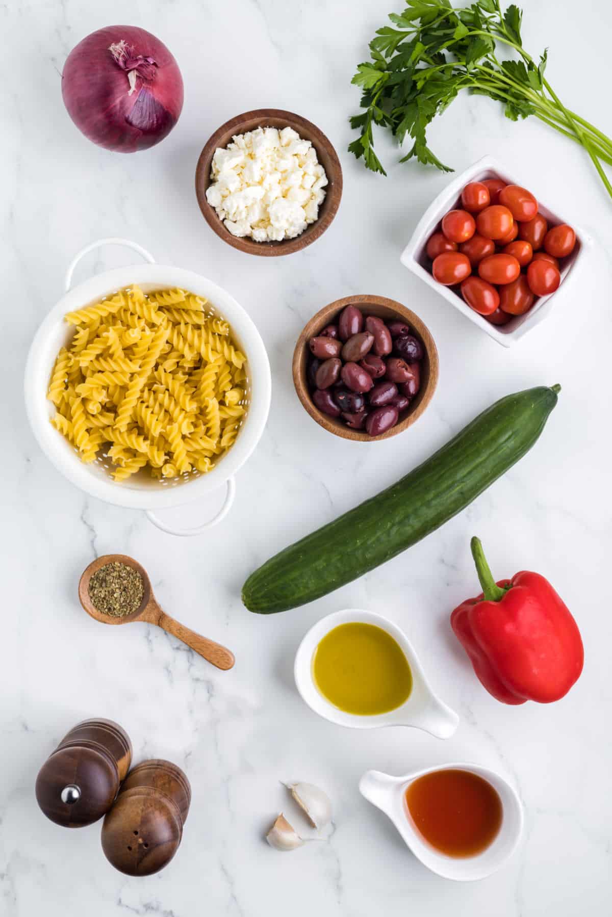 Ingredients for Greek pasta salad in dishes.